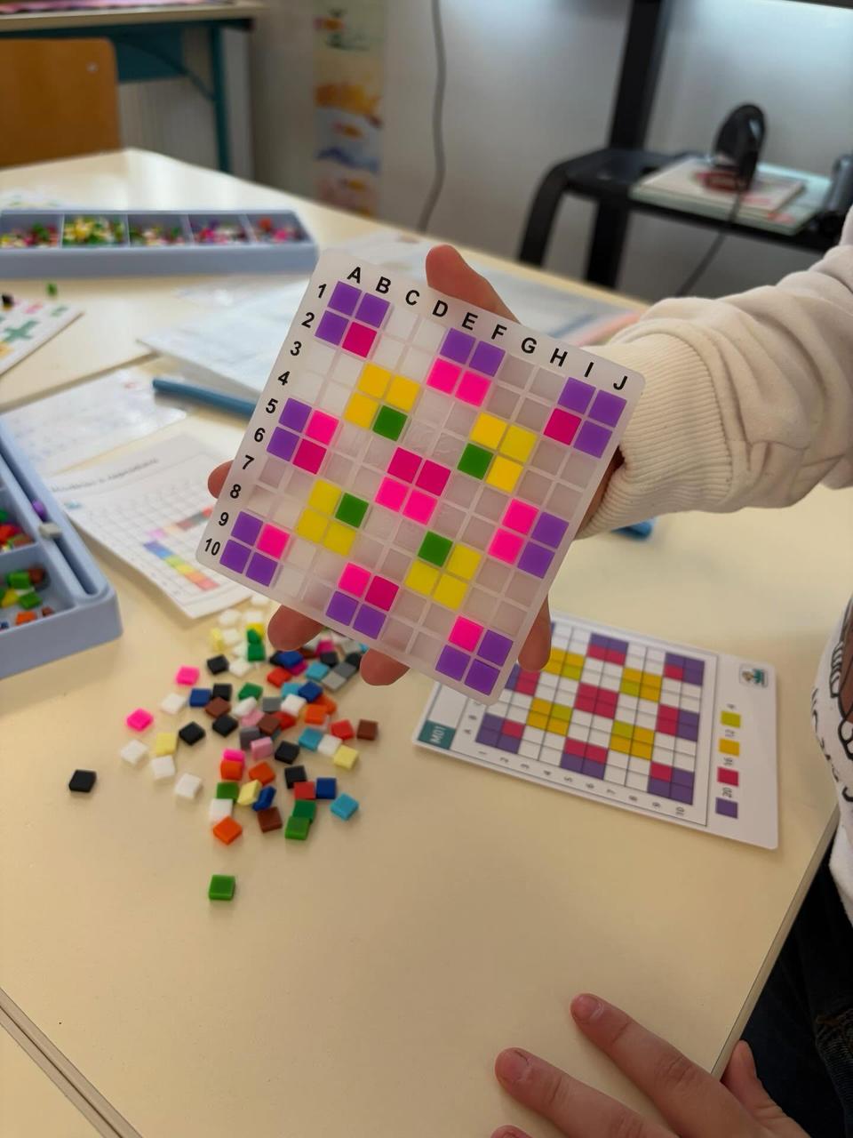 Élève montrant sa grille de pixel art en silicone terminée, en classe