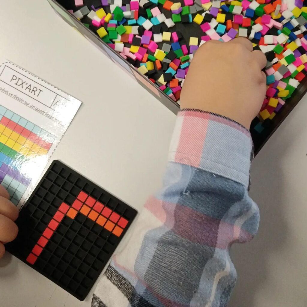 Main d'enfant piochant des pixels colorés pour reproduire un modèle sur sa grille Dodocraft