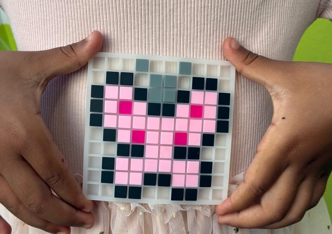 Enfant tenant fièrement sa grille pixel art terminée - Dodocraft