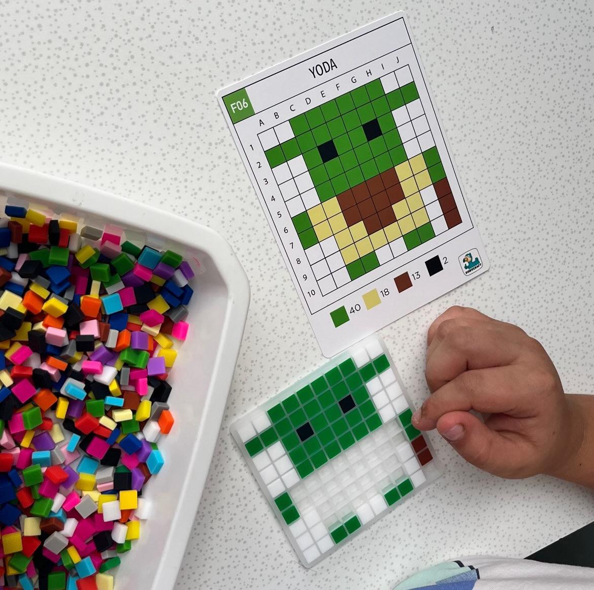 Enfant posant des pixels sur la grille avec la carte modèle Yoda - Dodocraft